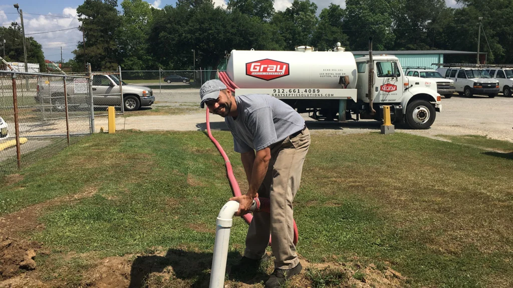 Gray Septic technician pumping a septic tank in a yard